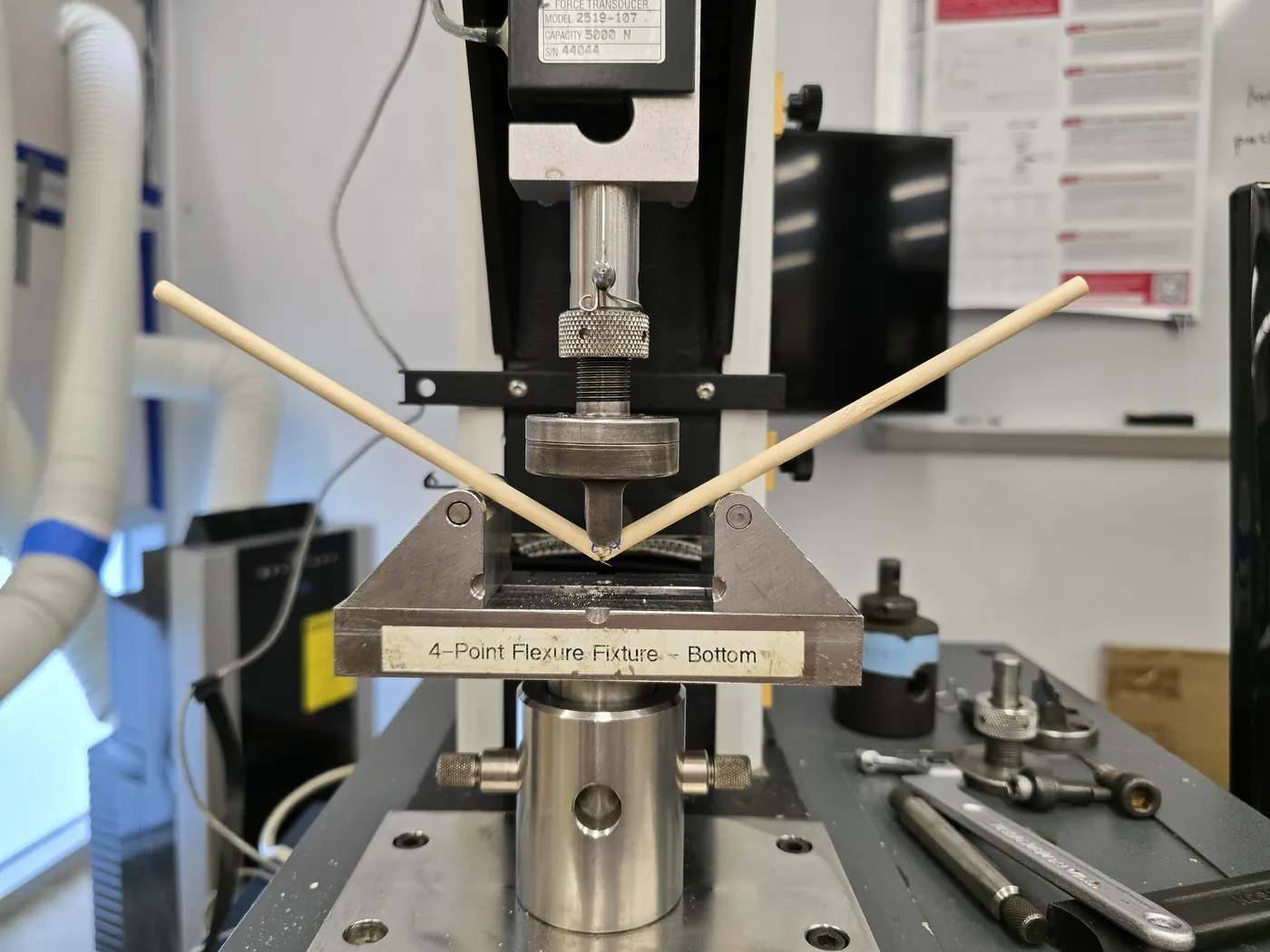Bamboo rod bending under the central loading tip of an Instron test fixture.