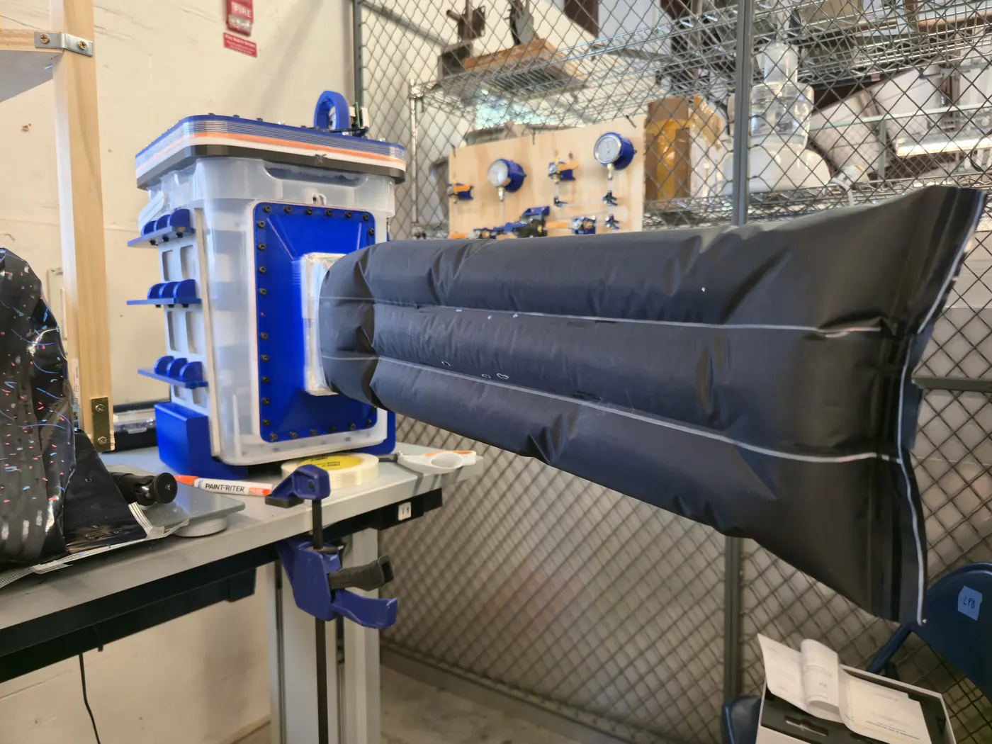 Physical vine robot with a three-partition soft body extended across a workshop bench.